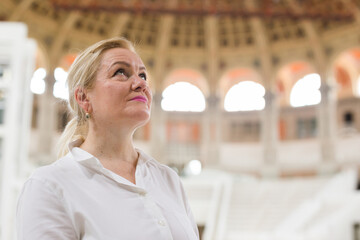 Closeup on attentive elegant senior woman wearing white blouse visiting museum