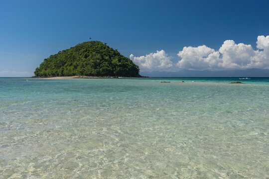 Mesmerizing view of the sandy Bon Bon Beach and a cliff with dense trees in the distance in Romblon