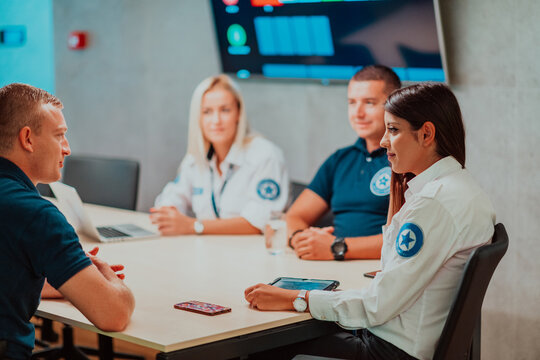 Group Of Security Guards Sitting And Having Briefing In The System Control Room They're Working In Security Data Center Surrounded By Multiple Screens