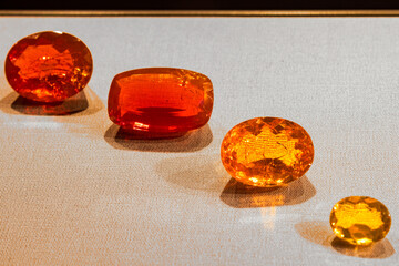 Row of shiny, bright amber gemstones in various shapes and sizes on display in a museum