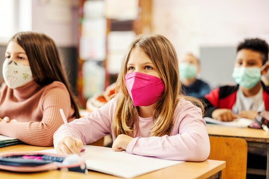 A schoolgirl writes schoolwork at class during covid 19.