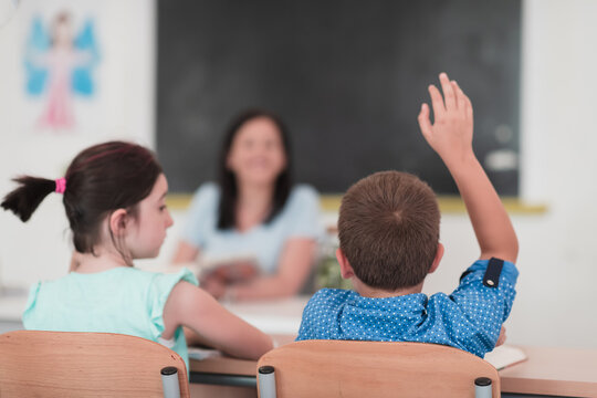 Multiracial group of kids wearing face masks working at class, writing and listening explanations of teacher in classroom