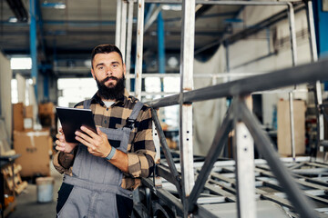 An industry worker checking on bus construction in vehicle production factory.