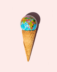 Minimalistic environment concept. Globe and ice cream cone on light pastel pink background. Creative ecological composition.