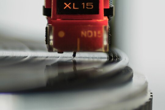 Closeup shot of a red phono cartridge with its needle on the turntable