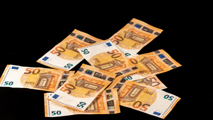 Pile of stacked fifty euro banknotes, on black background. Big plan