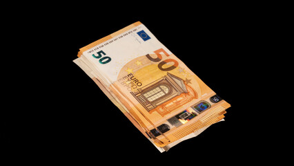 Wad of banknotes of fifty euros, on a black background