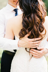 Obraz na płótnie Canvas Groom hands are on the back of the bride. Close-up
