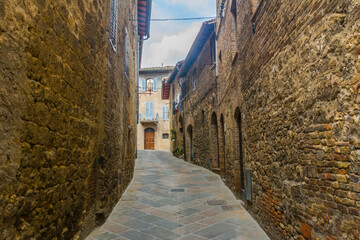 Fototapeta na wymiar Medieval alley with stone buildings at San Gemignano, Tuscany, Italy.