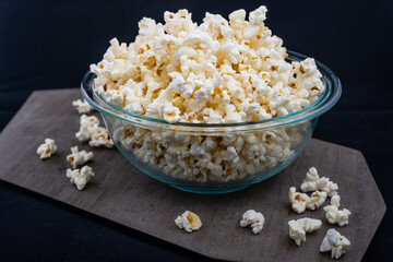 Horizontal orientation photo of a bowl of popcorn on a black background, an image of a bowl with a lot of popcorn isolated.