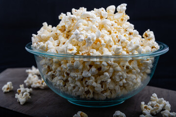 Horizontal closeup photo of a bowl full of popcorn on black background, closeup image of popcorn in...