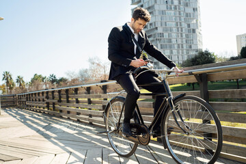 stylish young man on classic bike looks at his smartphone in the city