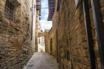 Narrow street and stone wall in the medieval city of San Gemignano, Tuscany, Italy.