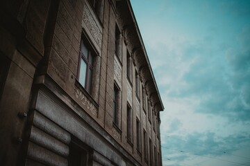 Low-angle shot of a brown building with windows and a background of blue evening sky - Powered by Adobe