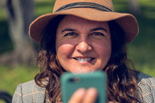 close up of woman smiling con cel phone and hat