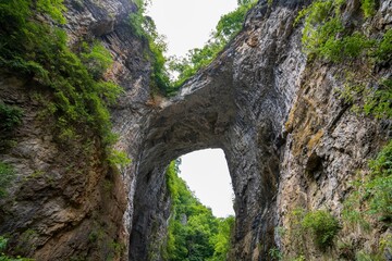 Beautiful Natural Bridge in Virginia covered by green lush trees and a group of visitors below