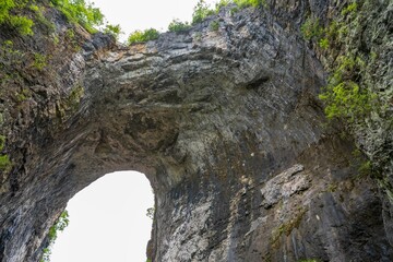 Beautiful Natural Bridge in Virginia covered by green lush trees and a group of visitors below