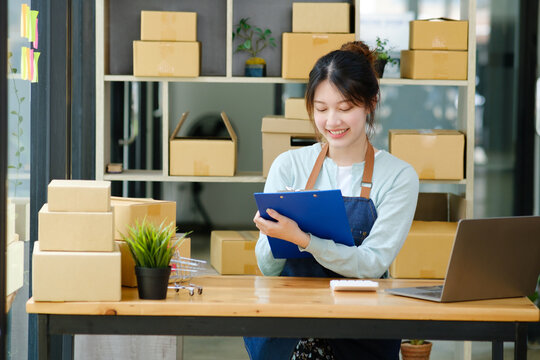 Young asian businesswoman onwer checking parcels list before delivering to customers.