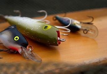 A close up of fishing lures on a wooden board.