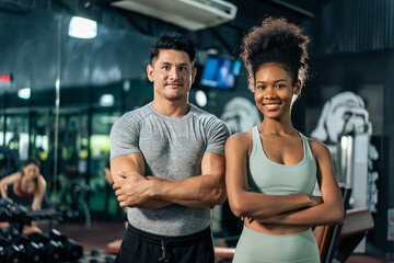 Portrait of African American woman and Caucasian man exercise in gym. 