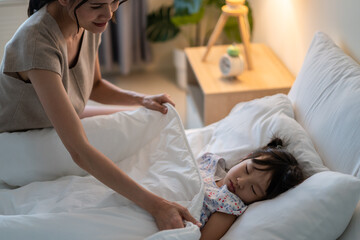 Asian beautiful mother put blanket on sleeping baby girl with gently.