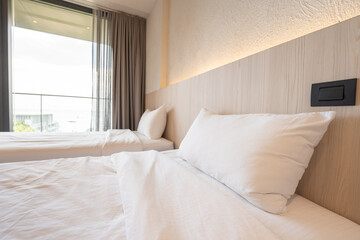 2 single beds with white bedding are in the cream bedroom of hotel that turn on the headboard light and open the gray curtain.