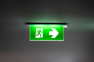 fire exit sign light box is hung on the ceiling in hotel walk way.