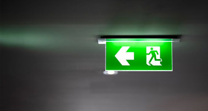 fire exit sign light box is hung on the ceiling in hotel walk way.