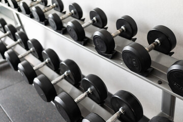 Obraz premium Stand with dumbbells. Sports and fitness room. Weight Training Equipment. Black dumbbell set, many dumbbells on rack in sport fitness center