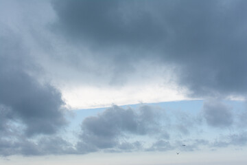 Fototapeta na wymiar Ciel. Nuages gris, sur bande de ciel bleu et trainée de nuage blanc.
