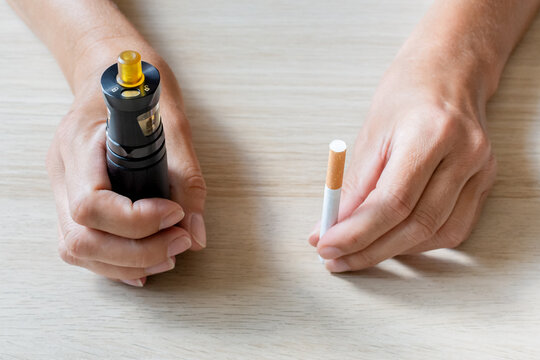 Arr&ecirc;ter de fumer gr&acirc;ce &agrave; la cigarette &eacute;lectronique.  Mains de femme tenant une cigarette dans une main et cigarette &eacute;lectronique dans l'autre.