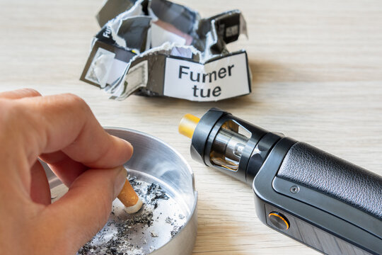 Arr&ecirc;ter de fumer gr&acirc;ce &agrave; la cigarette &eacute;lectronique.  Main de femme &eacute;crasant une cigarette, cigarette &eacute;lectronique et paquet chiffonn&eacute;. 