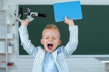 Portrait of funny pupil of primary school study in classroom at school. Excited schoolboy pupil...