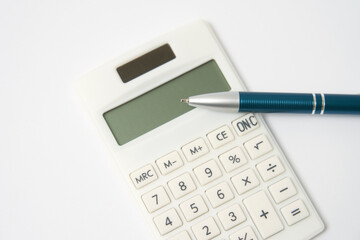 白背景にある電卓とボールペンのクローズアップ