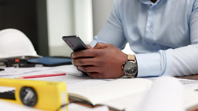 Phone, hands and communication with an architect, construction worker or building planner working in his office. Closeup of a business man reading or sending a text message while sitting at his desk