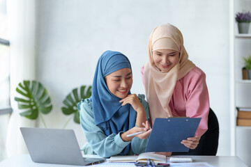 Two beautiful Muslim Asian businesswomen wearing hijab We are discussing work in various field there is an exchange of idea. and exchanging knowledge by using a laptop computer to work.