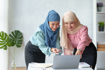 Two beautiful Muslim Asian businesswomen wearing hijab We are discussing work in various field there is an exchange of idea. and exchanging knowledge by using a laptop computer to work.