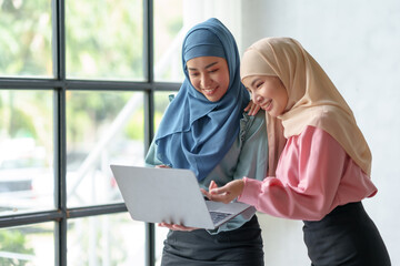 Two beautiful Muslim Asian businesswomen wearing hijab We are discussing work in various field there is an exchange of idea. and exchanging knowledge by using a laptop computer to work.