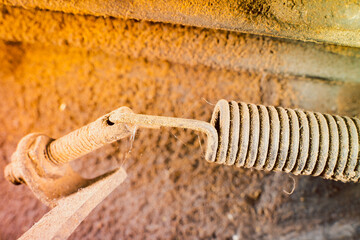 A close-up of the spring in the control mechanism of the walk-behind tractor. Compressed dirty...