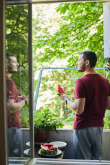 Man eating juicy red watermelon on the balcony. The concept of summer and delicious vegetables. Vertical photo.