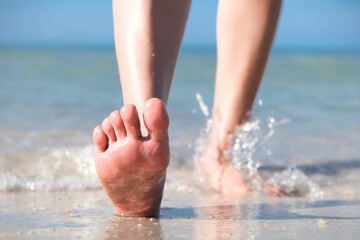 woman walking to sea and beach on a beautiful island Ocean foam wrapped around a girl's leg. Her legs touched the splashing water. Hit the skin on the legs and she walked in the soft sunshine morning