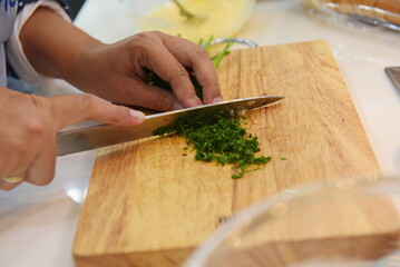 Almaty, Kazakhstan - 08.28.2015 : Slicing greens on a wooden board in the kitchen.