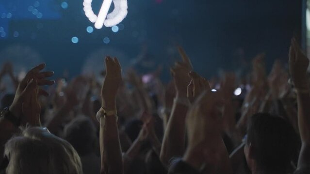 closeup of hands in crowd clapping their hands at a concvert, slowmotion