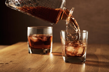 Whiskey is poured into a dammed glass with ice.