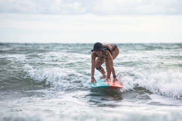 Fototapeta premium Woman surfer surfing and riding surfboard on the wave in the sea, surfing time, summer holidays travel