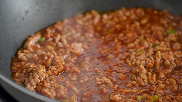 Stir-frying ground pork with hot spicy sauce when cooking mapo tofu cuisine at home.