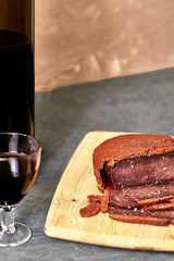 sliced basturma on a plate next to a bottle of wine and a glass