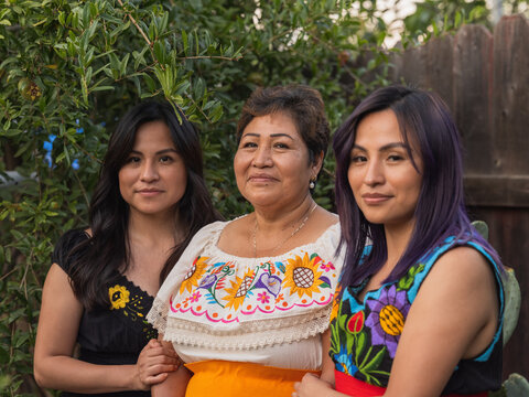 Three Indigenous women smiling and looking directly into the camera 