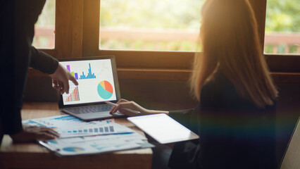 Businessman discussing and summarizing company profit with successful performance graph. A colleague examines the results of the quarterly report using a laptop and notebook graphing business idea.