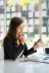 Obraz premium Asian business woman working in finance with laptop and smartphone, accounting concept.